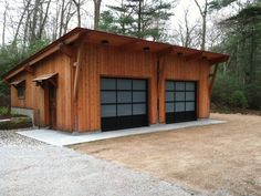 two garages in the middle of a wooded area with gravel and rocks around them