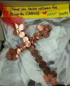 there is a cross made out of coins in a box with a note on it