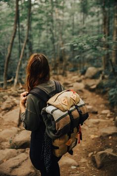 a woman with a backpack walking through the woods