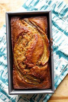 a loaf of banana bread sitting on top of a blue and white cloth next to a knife