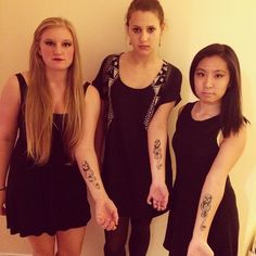 three women standing next to each other with tattoos on their arms