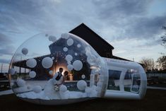 a bride and groom standing in an inflatable bubble