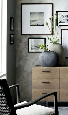 a living room with pictures on the wall and a vase sitting on top of a dresser