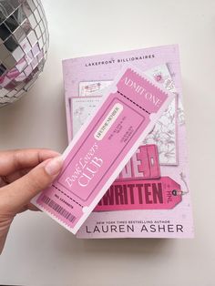 a person holding a pink ticket next to a silver ball on a white counter top