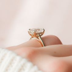 a woman's hand holding a ring with an oval shaped diamond in the middle