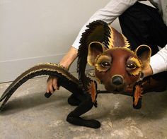 a man kneeling down next to a sculpture of a dog with wings on it's head