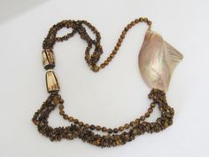 Vintage Jewelry Multi Strand Natural Tiger's Eye Shell Bead Necklace ....Measure of Necklace 34'' Length...Measure of Shell H 4 5/8'' W 3''...It's in very good condition. ### Tiger's Eye helps to rebalance the body on all levels, encouraging optimism and trust in the future. It brings brightness and light into all situations and shines insight onto all problems. Tiger's Eye brings good luck, abundance and prosperity to its wearer. In many ancient civilizations, it was used as a talisman against Brown Double Strand Beaded Necklace For Gift, Brown Shell Necklace With Round Beads For Gift, Multi-strand Brown Jewelry With Polished Beads, Artisan Double Strand Brown Necklace, Brown Polished Beads Costume Jewelry Necklace, Brown Polished Beads Costume Necklace, Brown Multi-strand Necklace With Polished Beads, Brown Large Beads Long Necklace, Brown Polished Bead Costume Necklace