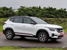 a white suv parked on the side of a road next to some grass and trees