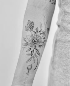 a woman's arm with a flower and butterfly tattoo on the left side of her arm