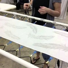 a woman standing next to a white surfboard on top of a metal rail in a room