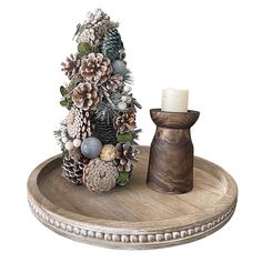 a wooden tray with pine cones and other decorations on it, along with a candle holder