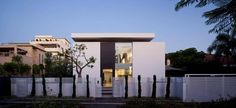 a modern house with white walls and black trim on the front door is lit up at night