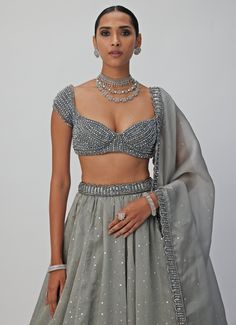 Introducing the stunning Grey Crystal and Sequin Embroidered Organza Lehenga Set, a masterpiece of craftsmanship that effortlessly blends traditional elegance with modern sophistication. Made from a luxurious mix of organza and georgette, the grey lehenga is intricately hand-embroidered, featuring shimmering sequins and crystal embellishments that add a dazzling, eye-catching effect. Paired with a jewelled blouse adorned with exquisite crystal detailing, this set exudes timeless beauty and charm. The look is completed with a delicately embroidered dupatta that enhances the outfit’s opulent design. Perfect for weddings, receptions, or festive occasions. Composition : Lehenga, Dupatta - Organza and Blouse - Georgette Care: Dry Clean Only and Vacuum Storage This product can be customized for Grey Lehenga, Vani Vats, Lehenga Dupatta, Organza Lehenga, Weddings Receptions, Vacuum Storage, Indian Wedding Wear, Embroidered Organza, Embroidered Dupatta