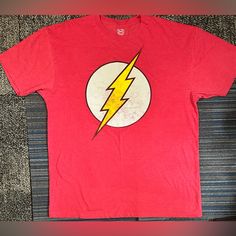 a red t - shirt with the flash logo on it