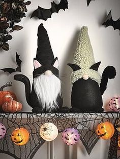 two black cats sitting next to each other on top of a shelf with halloween decorations