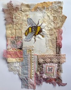 a piece of art made out of old fabrics and fabric with a bee on it