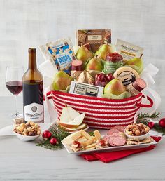 a red and white basket filled with wine, cheeses, crackers and fruit