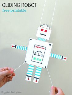 two hands holding up a paper robot hanging from strings with the text gliding robot free printable