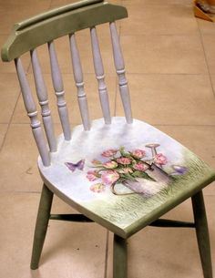 a wooden chair with flowers painted on it's back and seat, in front of a tile floor