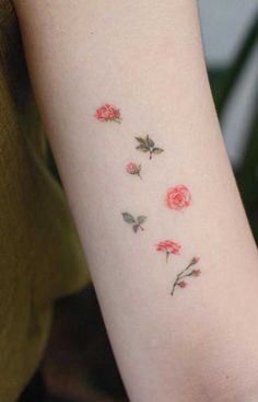 a woman's arm with three roses on the left side of her arm, and one is pink