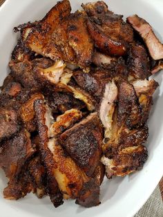 a white bowl filled with meat on top of a wooden table