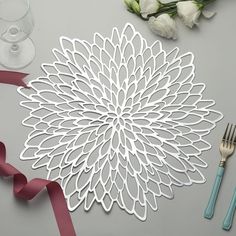 a table topped with white flowers next to a wine glass and silver utensils