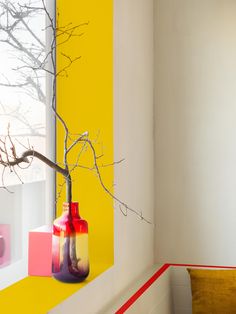 a yellow and red vase sitting on top of a window sill next to a tree