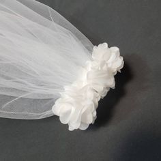 a bridal veil with white flowers on the top and bottom, sitting on a gray surface