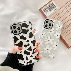 two cell phones that are next to each other on a white surface, one has a black and white flower design