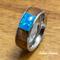 a wooden ring with blue opal inlays on the outside and inside, sitting on a table