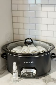 a crock pot with rolls in it sitting on a counter next to a bottle of deodorant