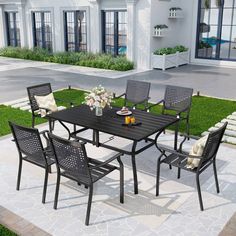 an outdoor dining table and chairs set on the ground in front of a white building