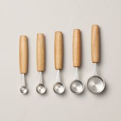 five spoons lined up next to each other on a white surface with wooden handles