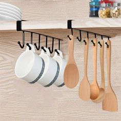 wooden spoons and spatulas are hanging on the wall