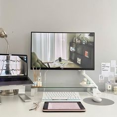 a desk with a computer monitor, keyboard and mouse on it next to a laptop