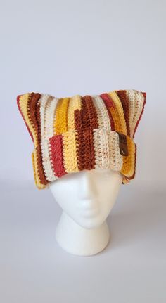 a white mannequin head wearing a multicolored knitted hat