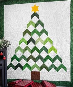 a quilted christmas tree is hanging on the wall next to a fireplace with presents under it