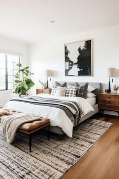 a bedroom with white walls and wooden flooring has a large bed in the middle