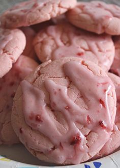 a plate full of cookies with pink icing on them