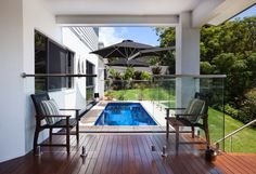 a deck with chairs and an umbrella next to a swimming pool