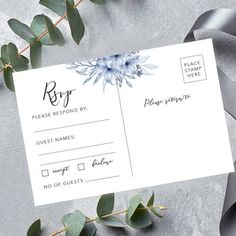 a white envelope with blue flowers and greenery on it next to a gray ribbon