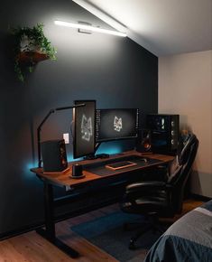 there is a desk with two monitors and a keyboard in the corner, along with a plant