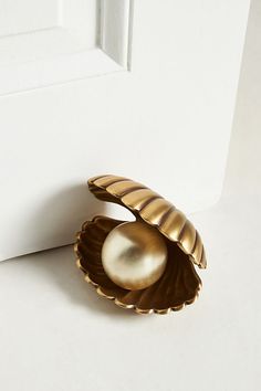 a gold shell with a pearl in the center on a white surface next to a door