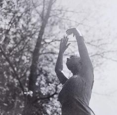 black and white photograph of a person reaching up to catch a frisbee in the air