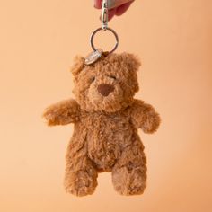 On a tan background is a brown bear stuffed toy on a silver loop and hook for adding to a bag or keychain. Jellycat Keychain, Jelly Cats Keychains, Bartholomew Bear Jelly Cat, Jellycat Wishlist, Jellycat Bartholomew Bear Bathrobe, Bartholomew Bear, Jellycat Bag Charm, Jellycat Bunny Keychain, Bear Bag