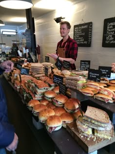 a man standing in front of a counter filled with sandwiches