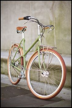 a green bike parked on the side of a street next to a building with a brown seat