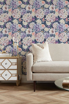 a living room scene with focus on the sofa and floral wallpaper