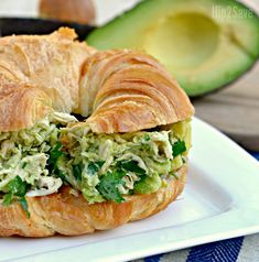 a croissant sandwich on a plate with avocado