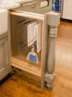 an open cabinet in the middle of a kitchen with cleaning supplies on top of it